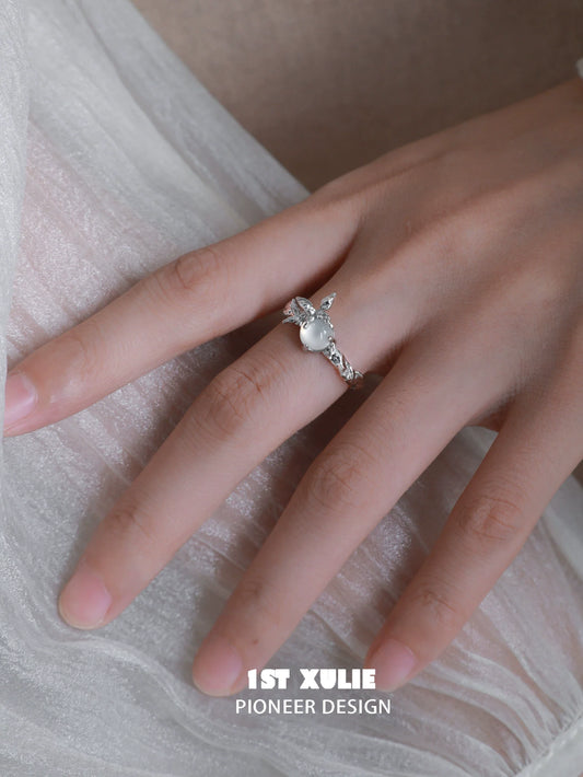 Elegant white agate butterfly silver ring showcased on a hand with a soft fabric background