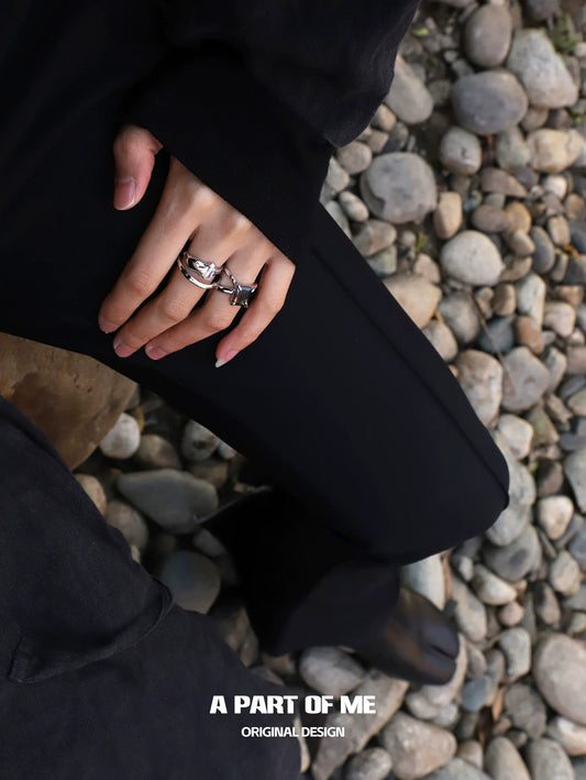 Clear quartz ring displayed on a hand with other unique rings against a rocky background