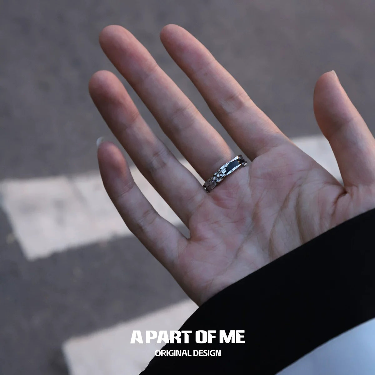 Elegant dark hills ring displayed on a hand against a street backdrop