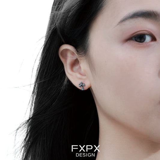 Close-up of bloody doll jewelry gothic cross stud earrings worn on an ear by a person