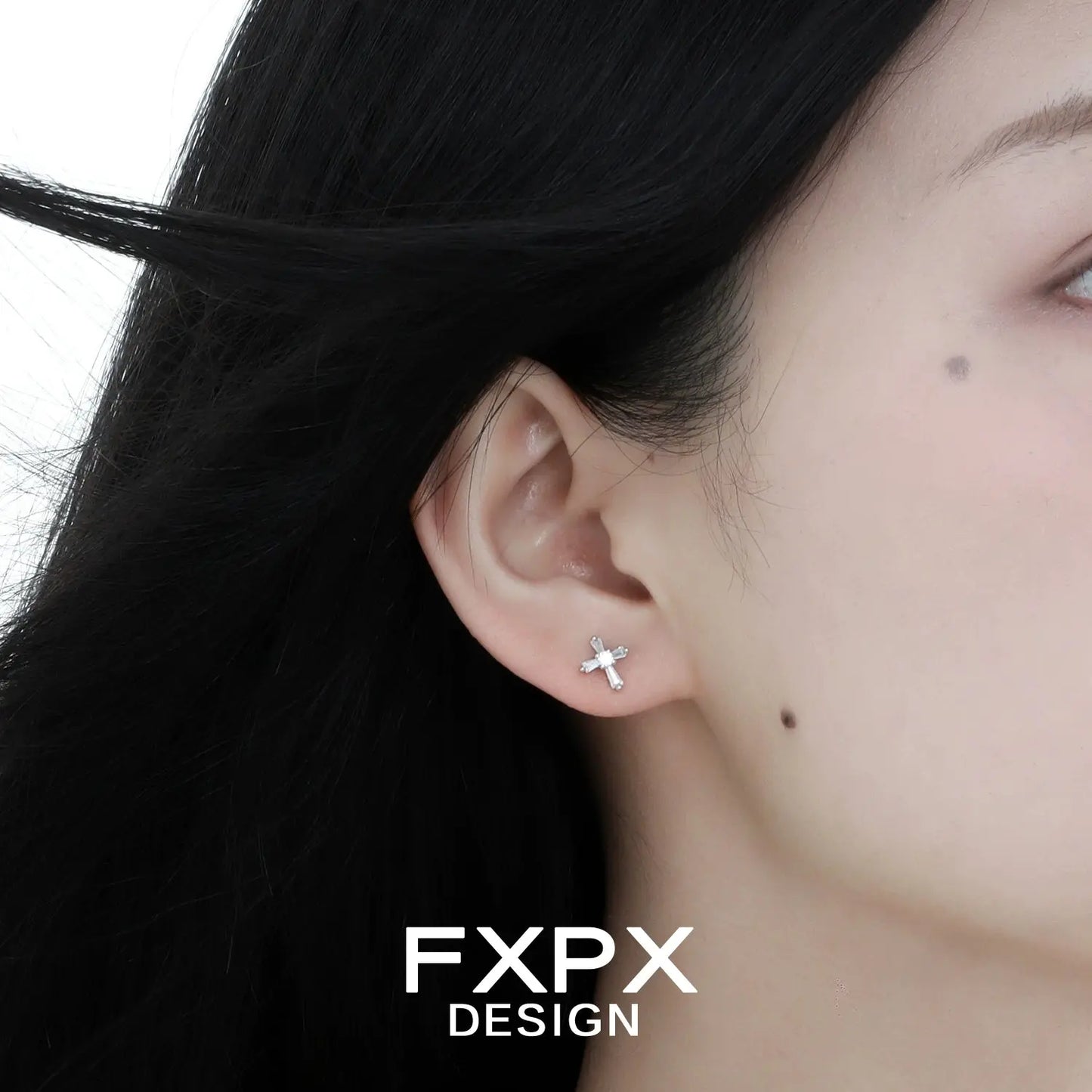 Close-up of bloody doll jewelry gothic cross stud earrings worn on ear by model with black hair