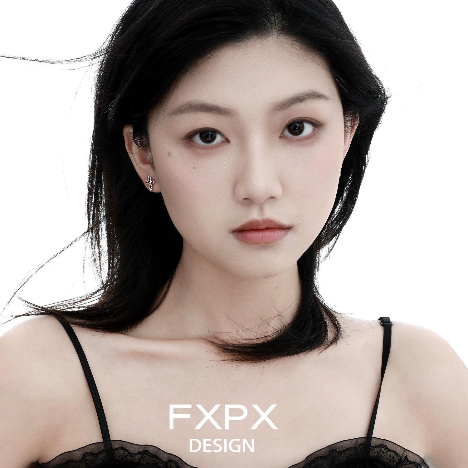 Young woman wearing bloody doll jewelry Y2K snake cross earrings in a minimalistic studio setting