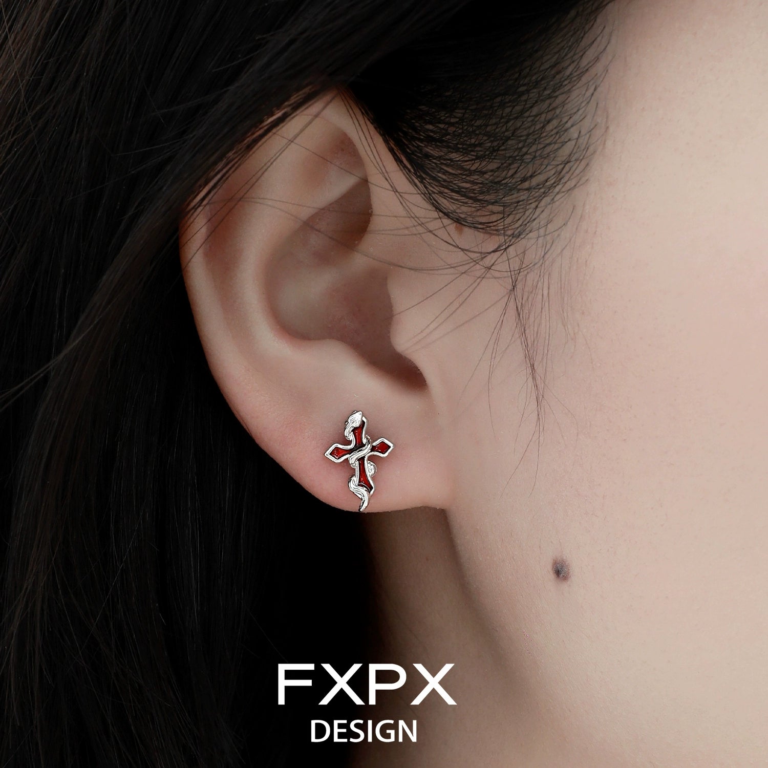 Close-up of bloody doll jewelry Y2K snake cross earrings worn on ear with silver design