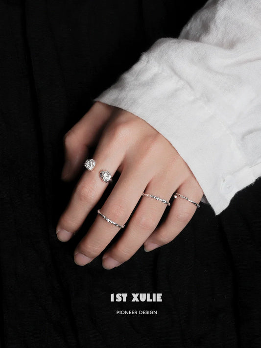 Two minimalist silver rings showcased on a hand with a white shirt, highlighting elegant simplicity