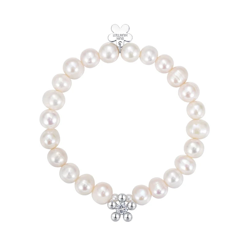 Elegant SUN HUNTER pearl bracelet for women featuring a silver flower charm and lustrous pearls