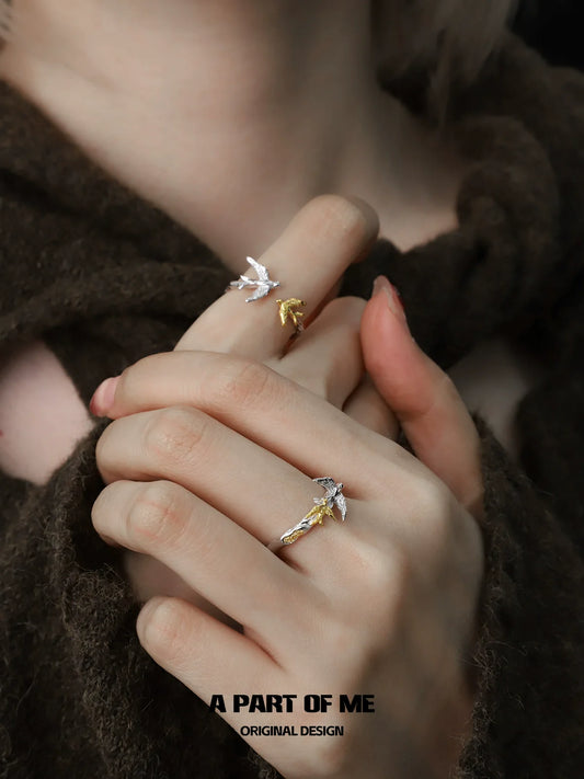 Soaring birds ring in silver and gold, showcasing a delicate design on styled hands