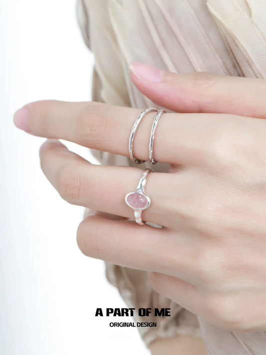 Elegant strawberry stone silver ring featured on a model's hand with delicate silver bands.