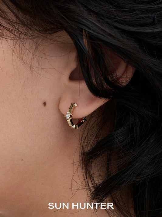 Elegant Maillard Iris stud earrings set worn on a model's ear highlighting their unique design