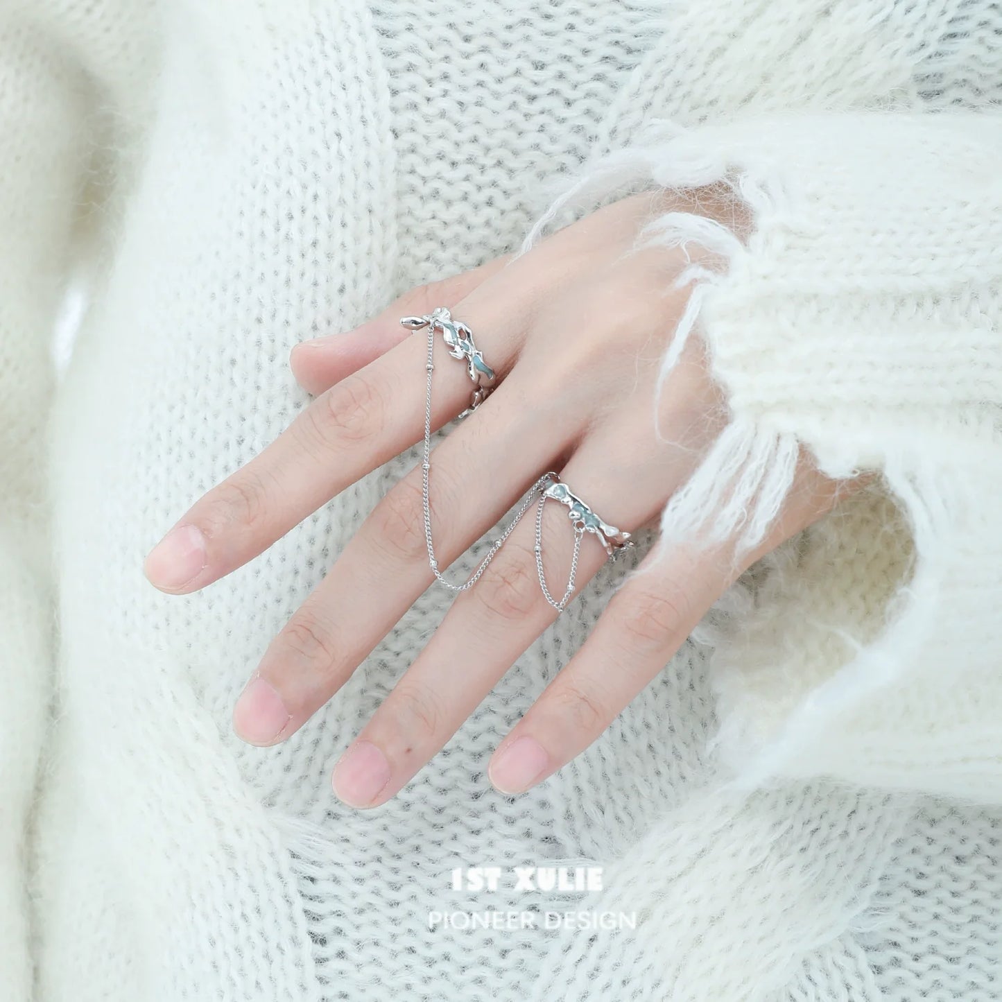Silver chain double ring design displayed on a hand wearing a cozy sweater