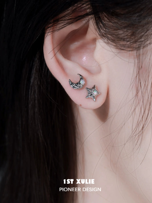 Silver cosmic moon and star earrings with sparkling details on a model's ear