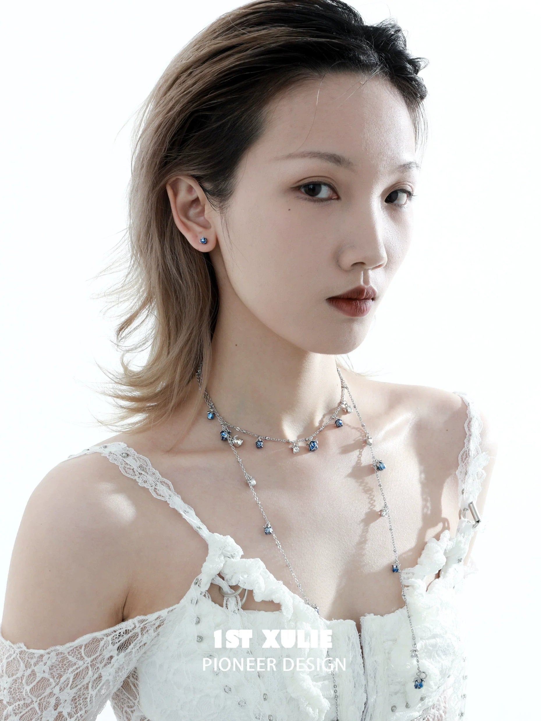 Model wearing crimson and azure rose stud earrings with delicate features and a lace dress
