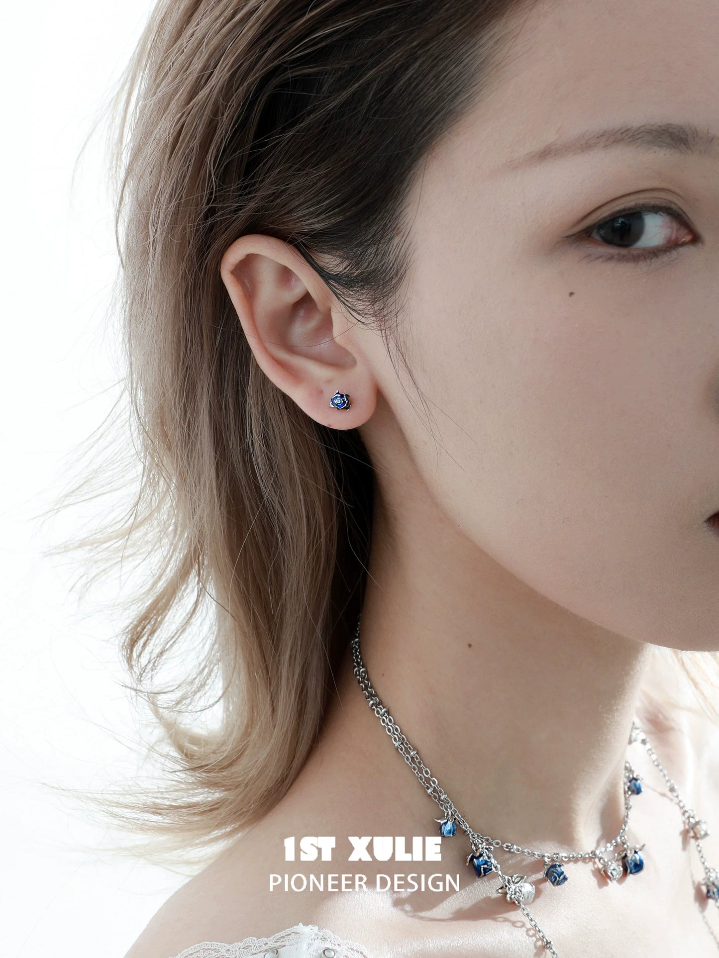 Elegant crimson and azure rose stud earrings worn by a model, showcasing unique design and color contrast