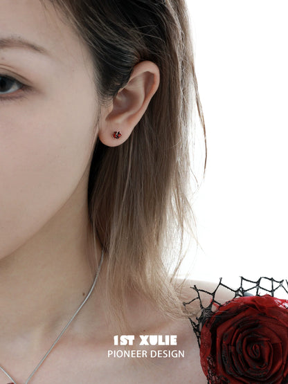 Crimson and azure rose stud earrings showcased on a model's ear with delicate styling