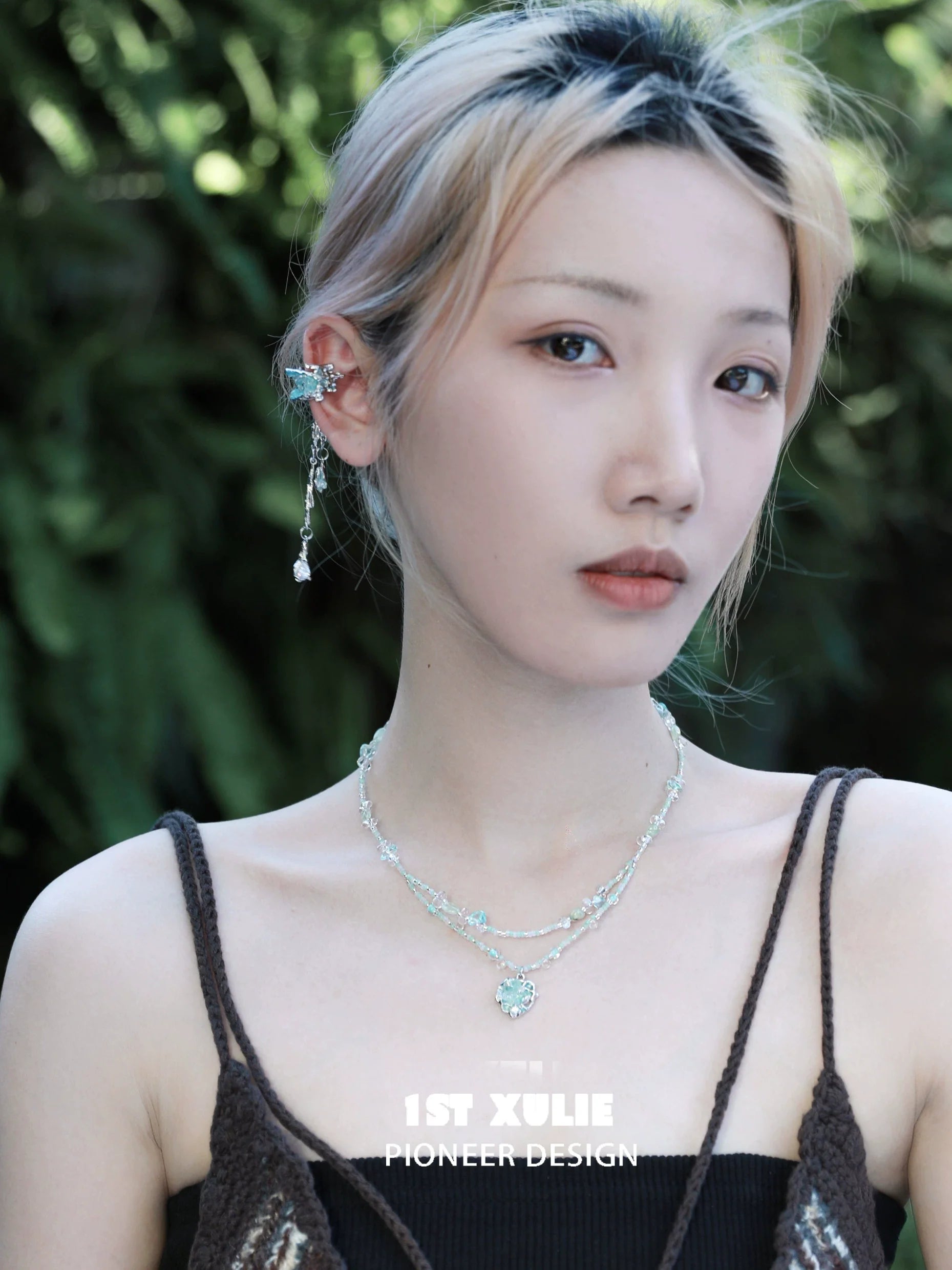 Model wearing 1STXULIE crystal tassel ear clips with stylish layered necklaces in an outdoor setting