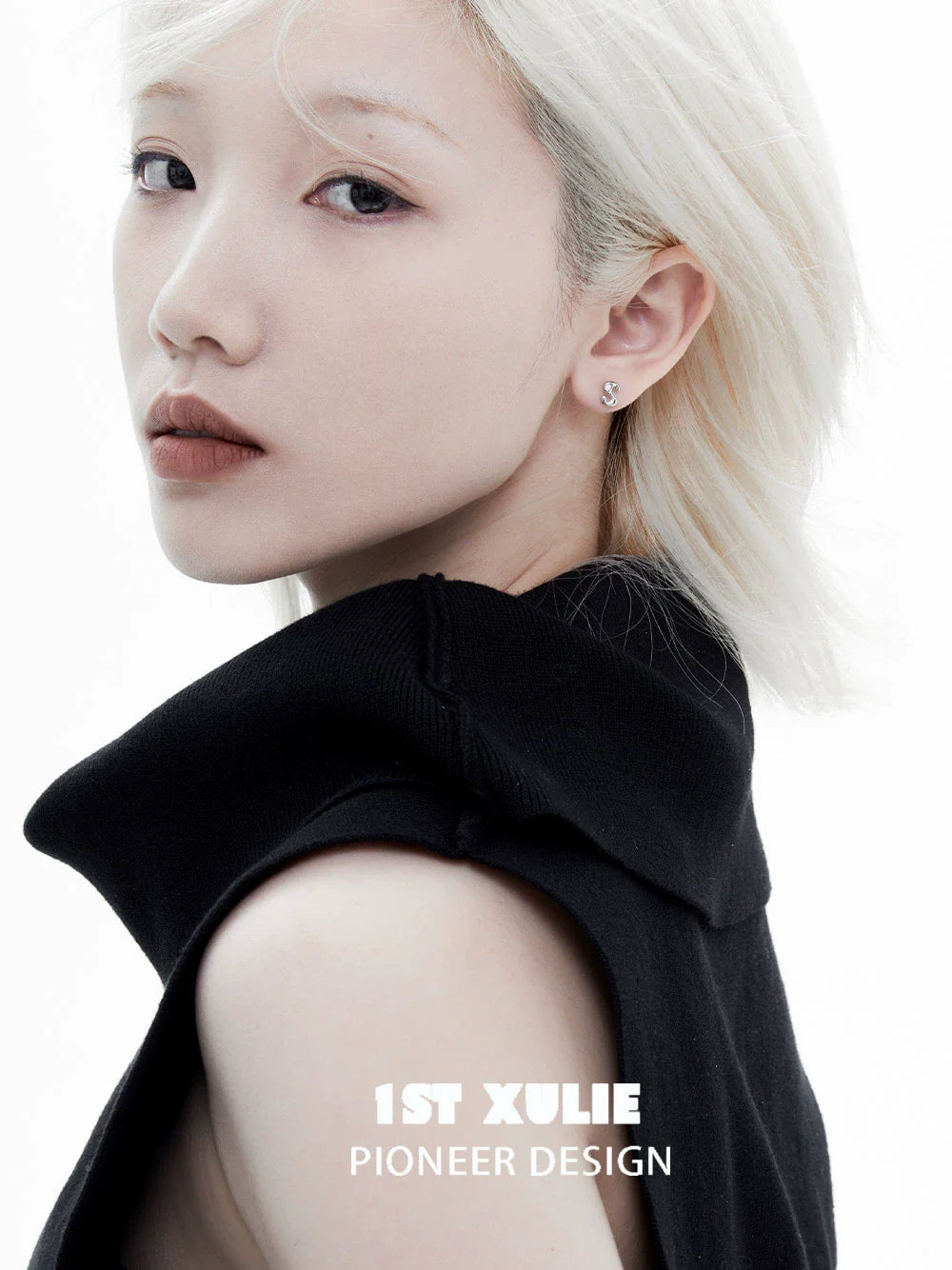 Model showcasing edgy letter silver stud earrings in a stylish black outfit