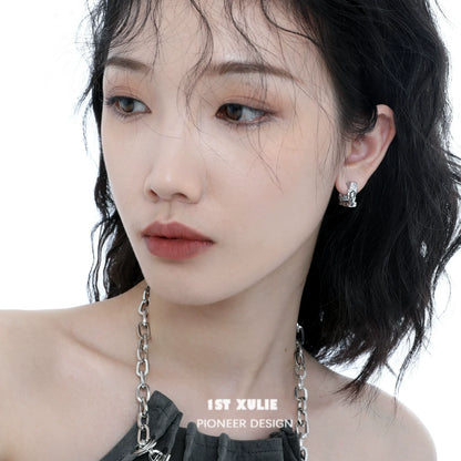 Frosted geometric earrings displayed on a model with wavy hair and natural makeup