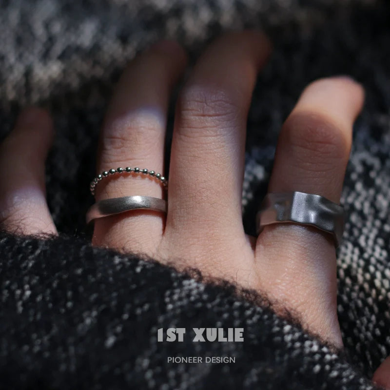 Futuristic silver ring displayed on a hand alongside a beaded silver ring for modern accessories