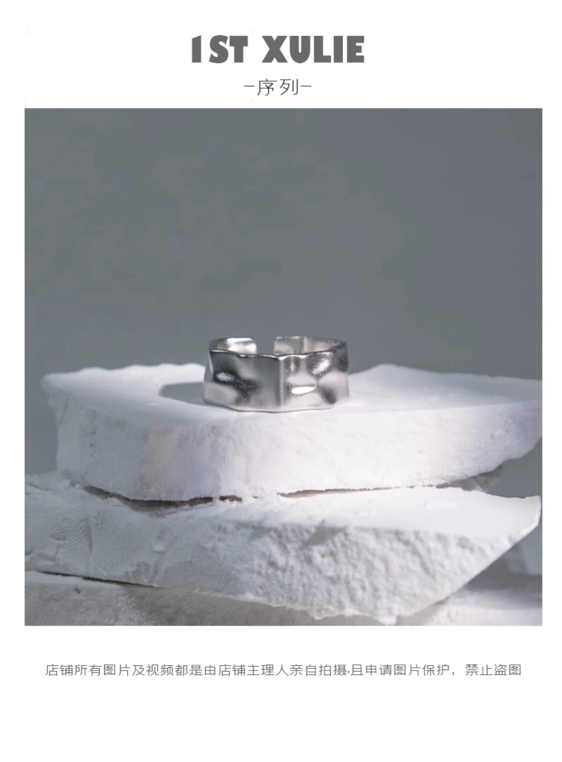 Futuristic silver ring displayed on textured white stones for a modern jewelry collection