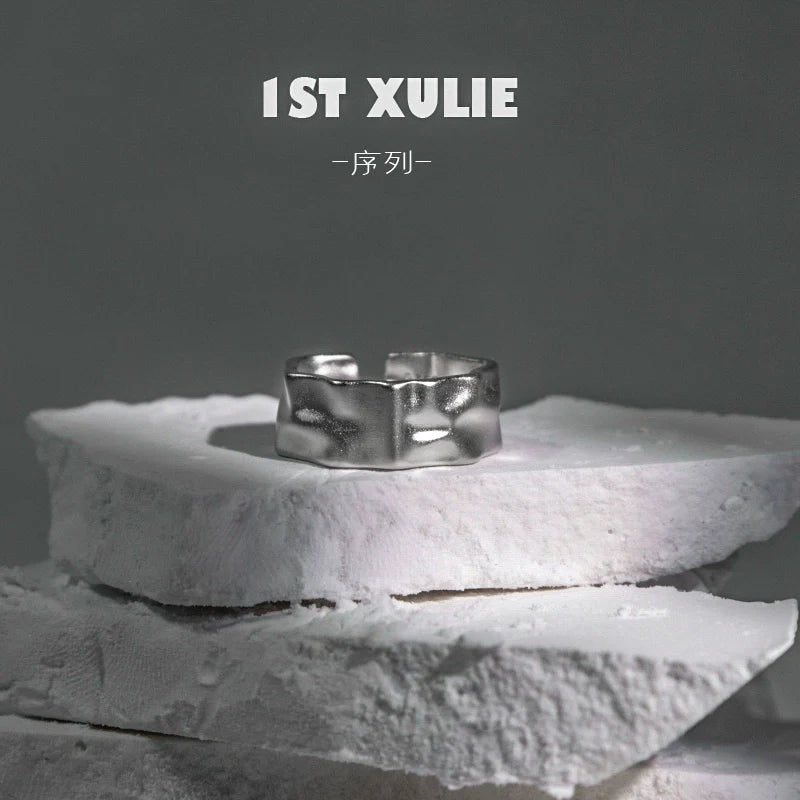 Futuristic silver ring displayed on textured white stone for contemporary fashion enthusiasts