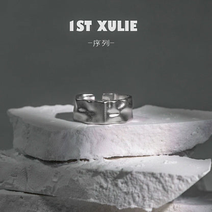 Futuristic silver ring displayed on textured white stone for contemporary fashion enthusiasts
