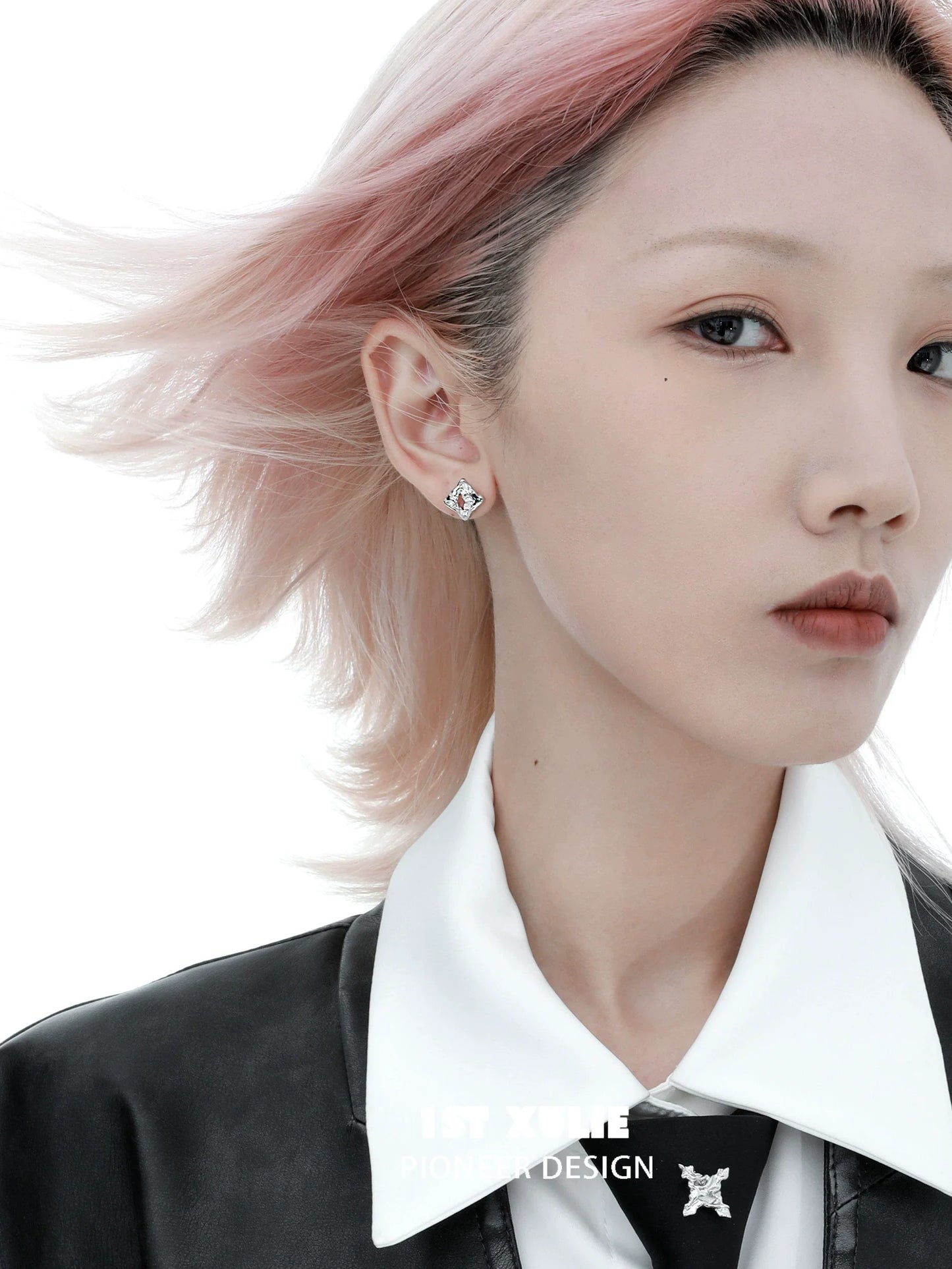 Geometric silver earrings displayed on a model with pink hair, styled elegantly in a black outfit