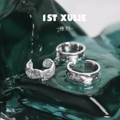 Three 1STXULIE minimalist frosted ear cuffs displayed elegantly on a shiny surface