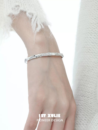 Minimalist silver bracelet from 1ST XULIE displayed on a hand with a soft, textured sweater