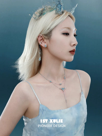 Elegant model wearing a moon double necklace with shimmering details and a soft blue outfit