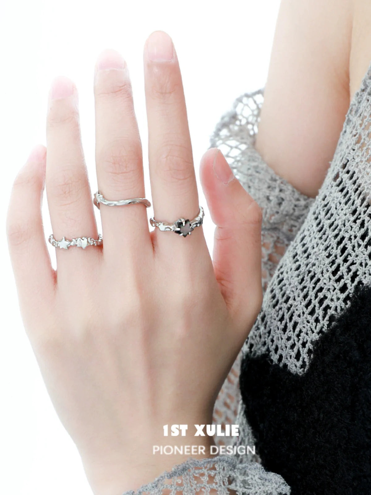 Silver star couple ring displayed on a hand with multiple rings, showcasing a sleek design