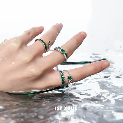 Slytherin inspired green snake ring set featuring intricate designs on a hand above water