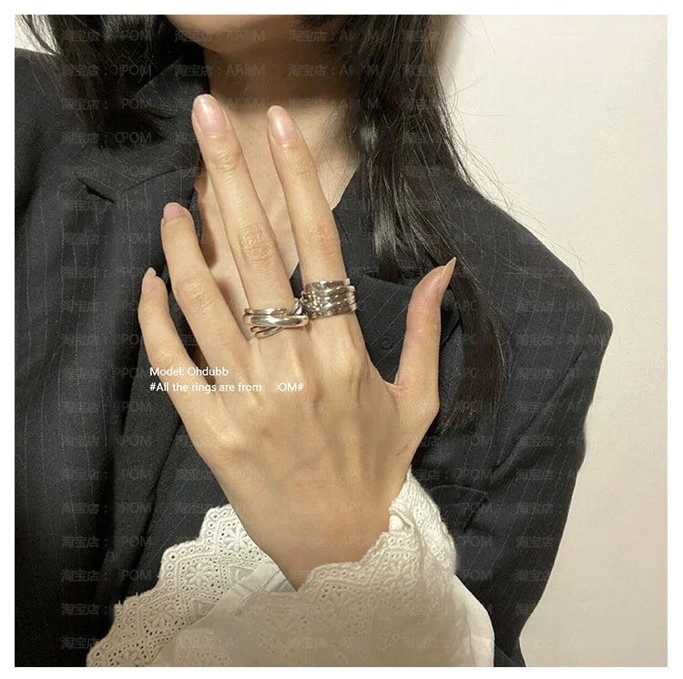 Model wearing silver bandage wrap punk ring along with other stylish rings on a hand in a chic outfit