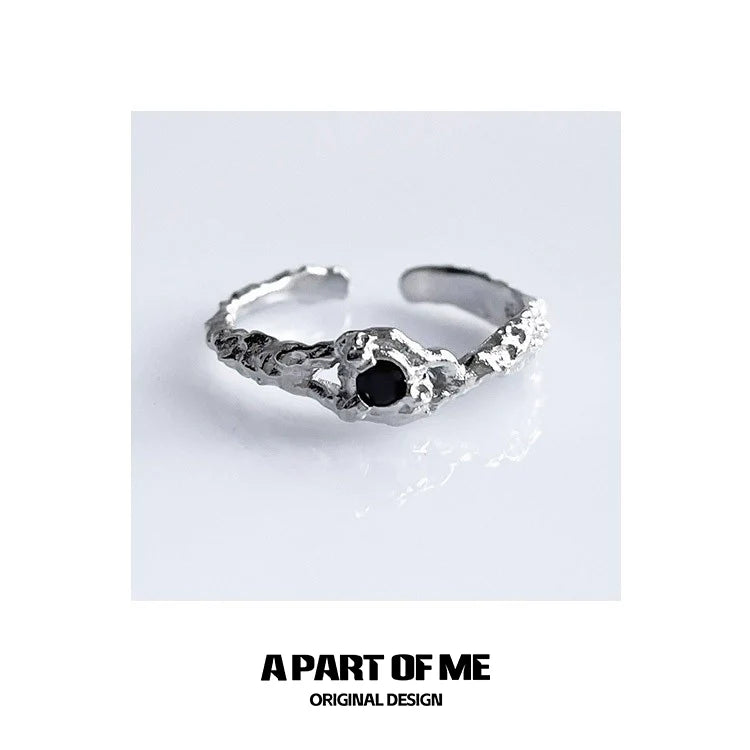 A unique A PART OF ME black crown ring featuring a textured design and a black stone centerpiece