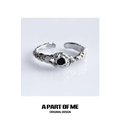 A unique A PART OF ME black crown ring featuring a textured design and a black stone centerpiece