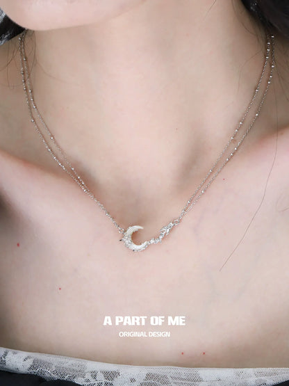 Elegant crescent moon necklace on a layered silver chain, perfect for stylish accessories.