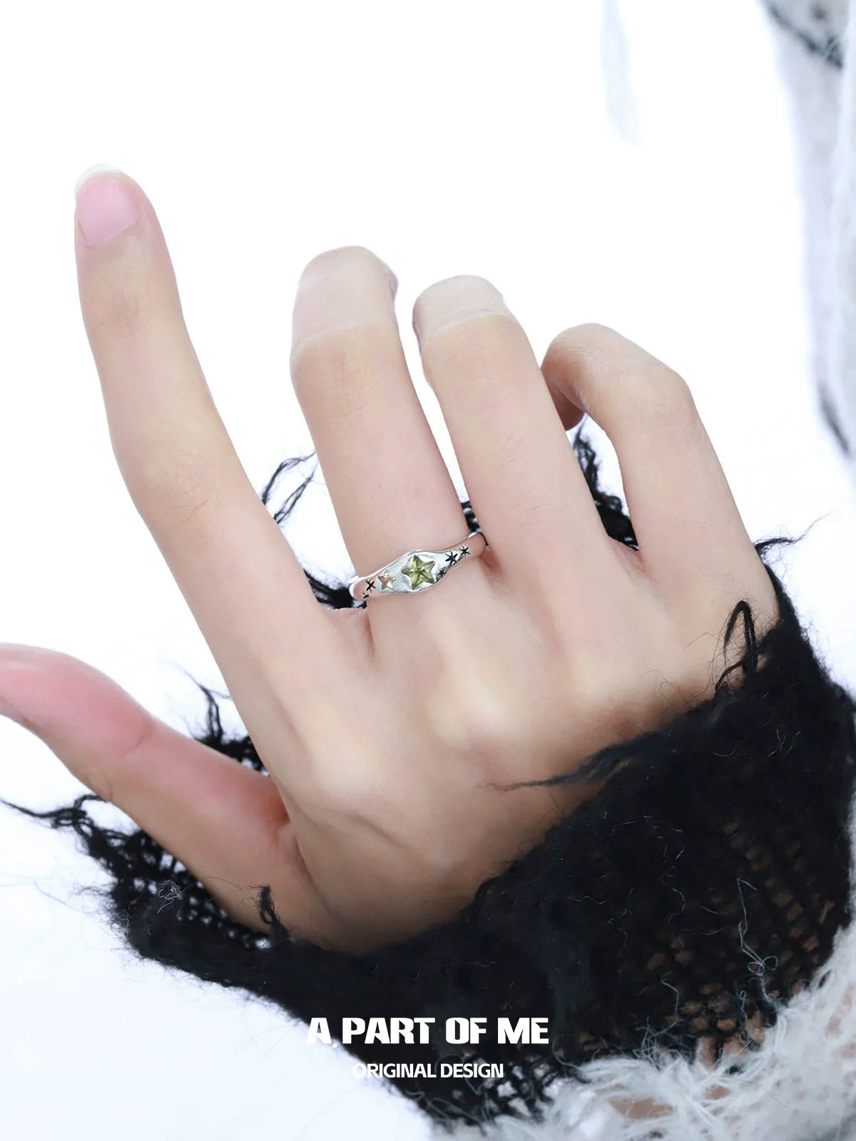 A hand wearing a delicate dreamy star ring with a silver setting and a unique gemstone design