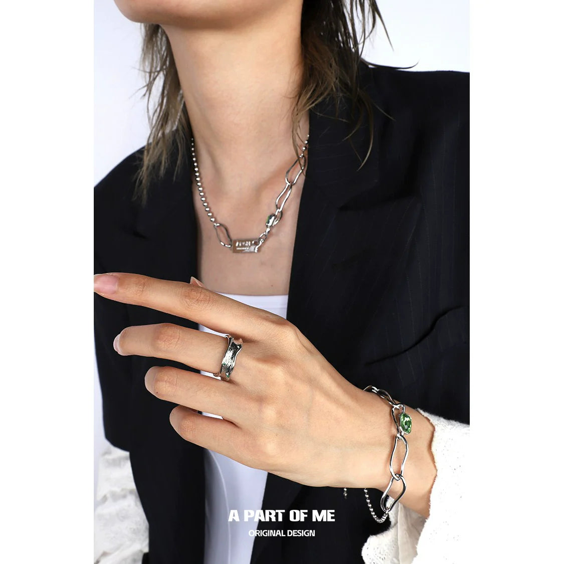 Person wearing a silver chain bracelet and a green crown punk ring for a stylish and edgy look
