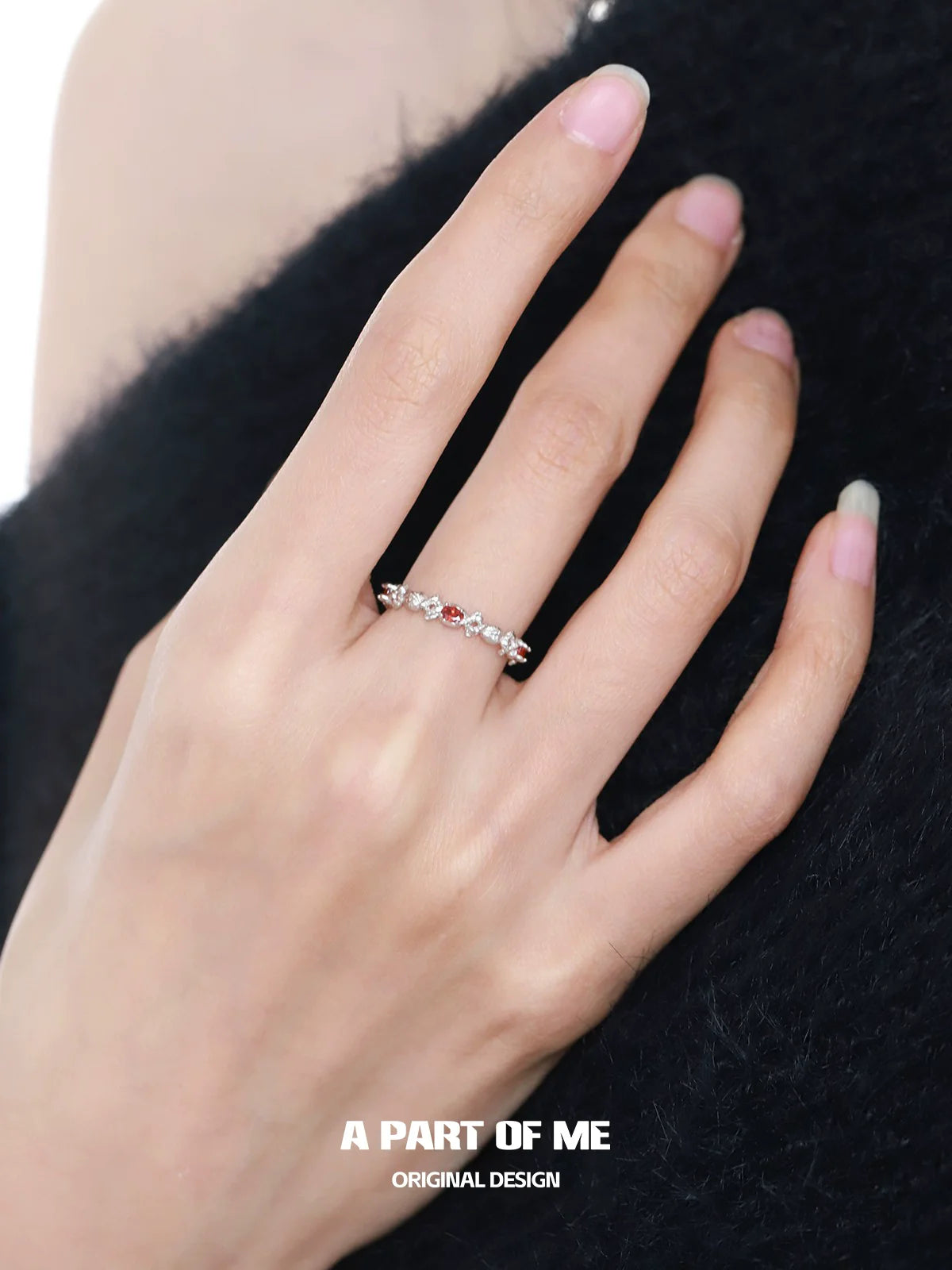 A delicate silver ring adorned with red candy ring details, worn on a hand with elegant nails