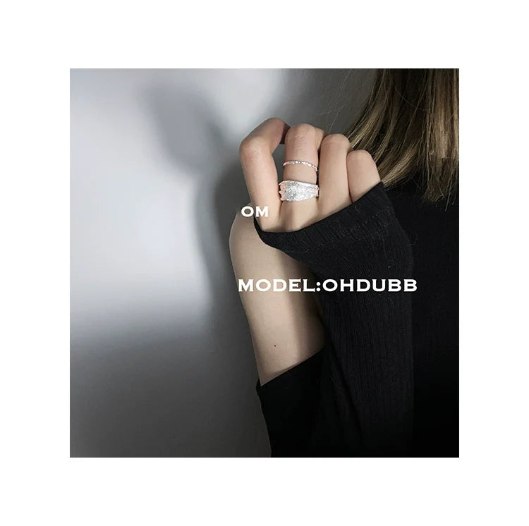 Silver bandage ring showcased on a hand with a stylish black sweater for a trendy look