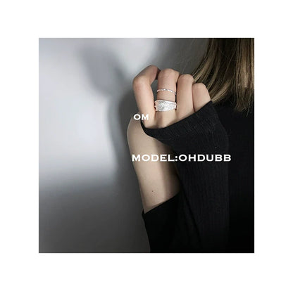Silver bandage ring showcased on a hand with a stylish black sweater for a trendy look