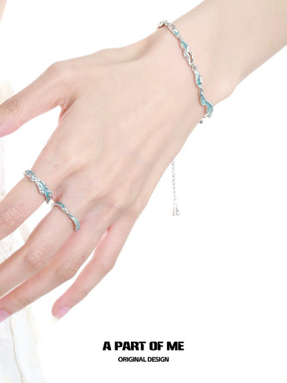 A hand wearing a silver bracelet and a white orchid love ring with floral design details
