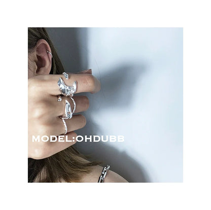 Close-up of a hand displaying a Y2K silver statement ring among other stylish rings