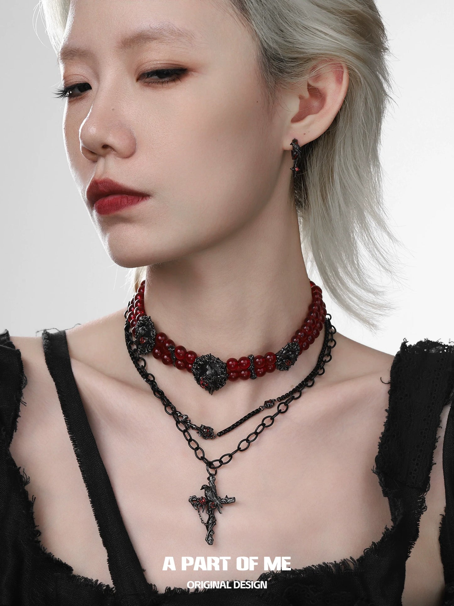 Gothic raven necklace layered with red beads and a cross pendant for a dramatic look