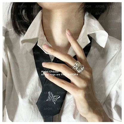 Model wearing a lace pleated silver ring on her finger, paired with a white shirt and black tie
