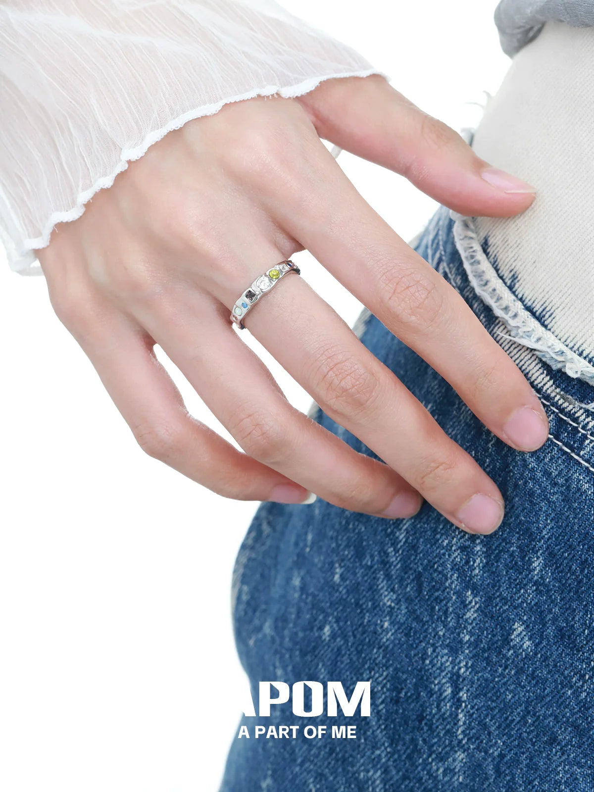 Silver rainbow gemstone ring worn on a hand with casual denim jeans for a stylish look