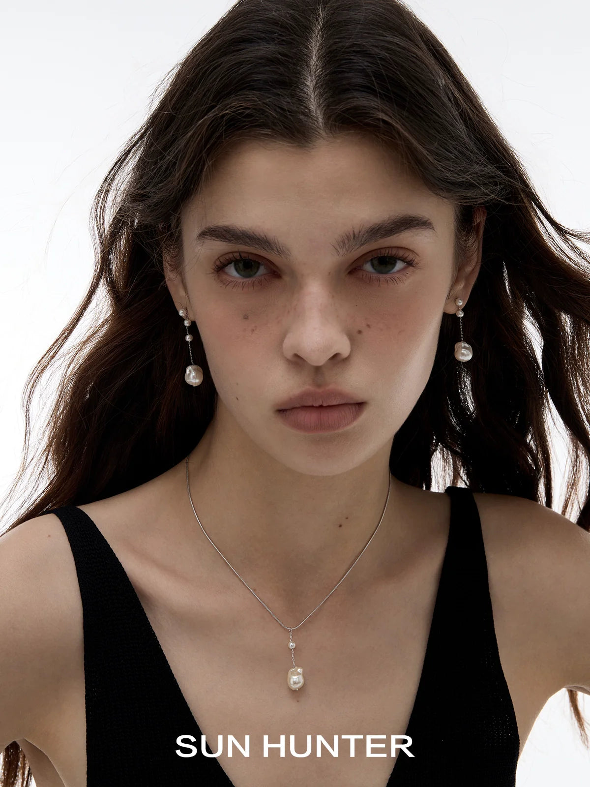 Baroque pearl earrings in silver showcased on a model with a sleek black top