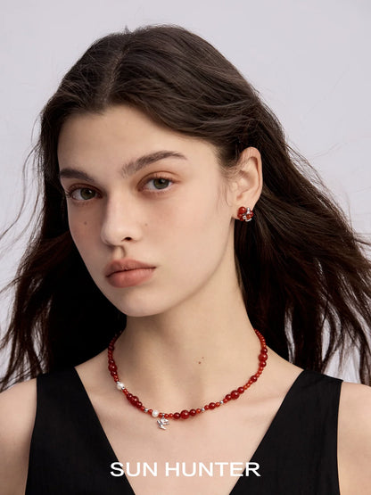 Elegant model wearing black agate earrings paired with a simple red bead necklace from SUN HUNTER
