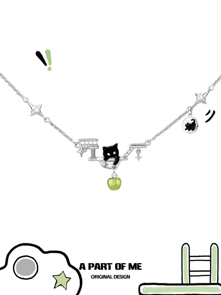 A PART OF ME black cat necklace featuring silver chain, black cat charm, and green apple pendant