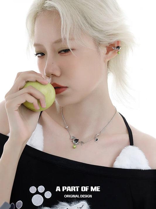 Elegant black cat necklace by A PART OF ME worn by a model holding a green apple