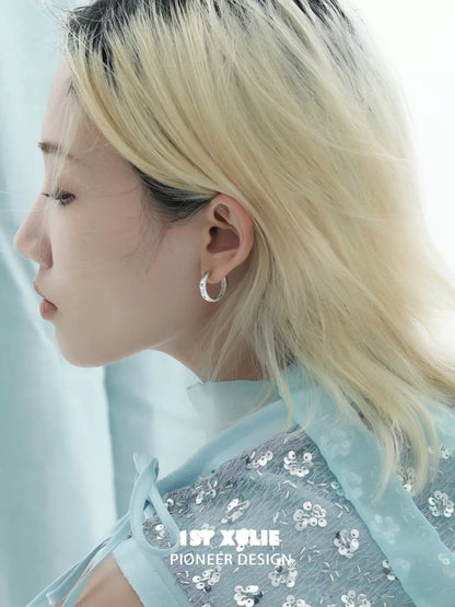 Elegant blue butterfly earrings displayed on a model with long hair in a soft blue outfit