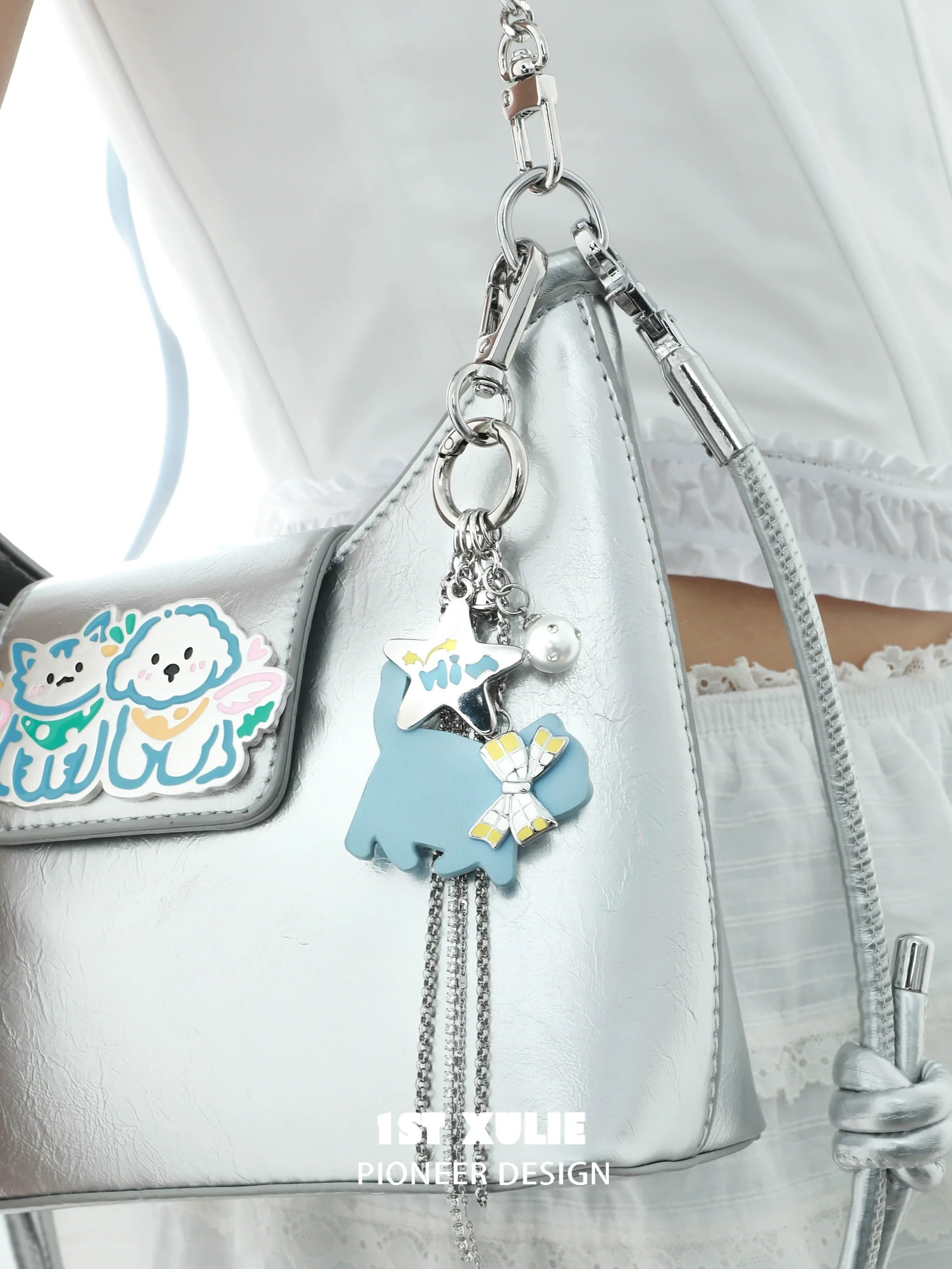 Blue cat keychain necklace with charms attached to a silver handbag for stylish accessories